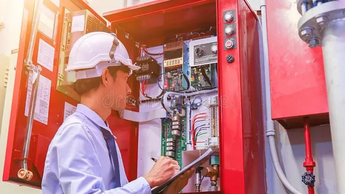 Technician inspecting a commercial fire alarm control panel